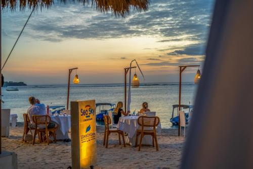 a group of people sitting at tables on the beach at Lembongan Beach Club & Resort in Nusa Lembongan