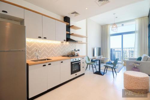 a kitchen with white cabinets and a table with chairs at WelHome - Fancy 1BR Apt at Dubai Hills near Dubai Hills Mall in Dubai