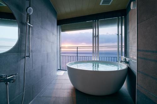 a bath tub in a bathroom with a view of the ocean at samana hotel Yakushima in Yakushima