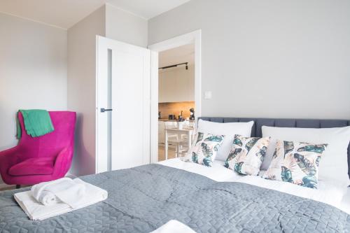 ein Schlafzimmer mit einem Bett und einem rosa Stuhl in der Unterkunft Apartament Bałtycka & Bike Room in Kołobrzeg
