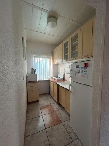 a small kitchen with a white refrigerator and cabinets at Domek letniskowy przy lesie in Rowy
