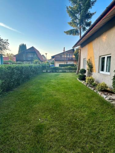 a yard with green grass next to a house at Domek letniskowy przy lesie in Rowy