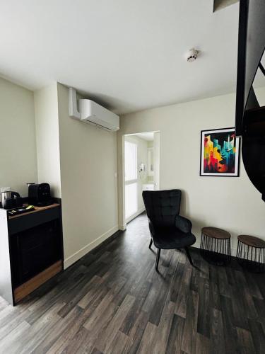 an empty living room with a chair and a window at Hotel Wood Inn Bordeaux Aéroport in Mérignac
