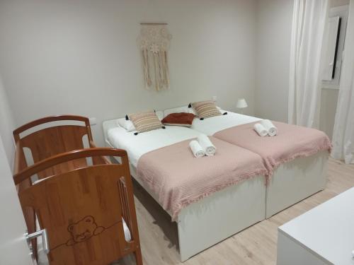 a bedroom with two beds with pink sheets and a chair at Casinha de Santo Amaro in Ourém