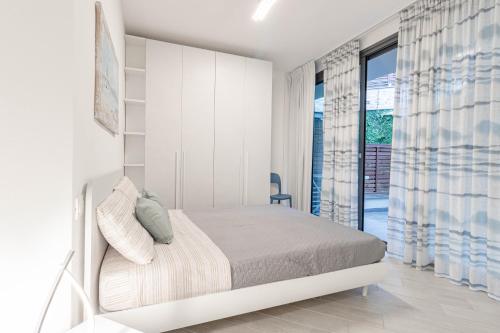 a white bedroom with a bed and a window at H11 LUXURY 3B - Porto - Piscina - Jacuzzi in Santo Stefano al Mare