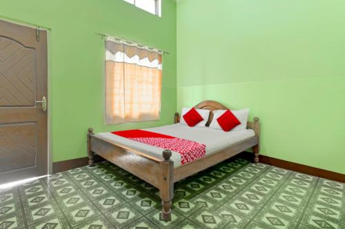 a bedroom with a bed with red pillows and a door at Hotel O WELCOME RESORT & FAMILY RESTAURANT in Barpeta