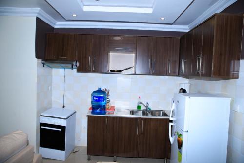 a kitchen with wooden cabinets and a white refrigerator at IZA Serene city centre apartments in Kigali