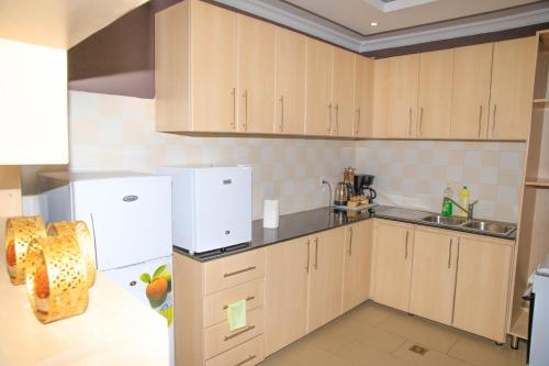 a kitchen with wooden cabinets and a white refrigerator at IZA Serene city centre apartments in Kigali
