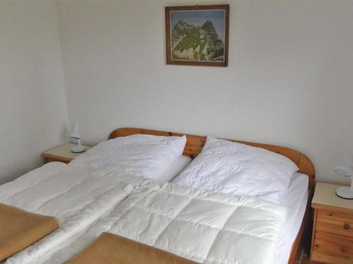 a white bed in a bedroom with a picture on the wall at Ferienhof Nonnevitzer Strand, Typ B in Dranske