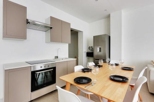 une cuisine et une salle à manger avec une table et des chaises en bois dans l'établissement Cosy apartment - 1BR-6P - Batignolles, à Paris