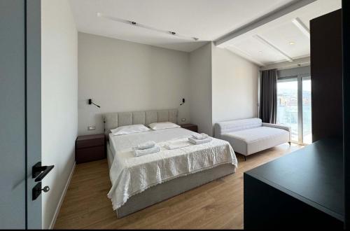a white bedroom with a bed and a chair at Penthouse Sea view Apartments in Sarandë