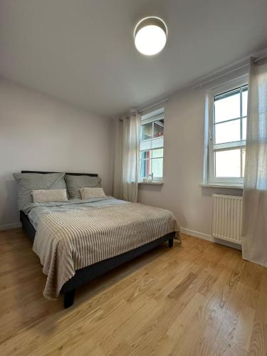 a bedroom with a large bed and two windows at Chillout u Oli Apartament nad samym jeziorem in Ostróda