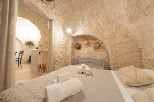 a bedroom with a bed in a stone wall at Trulli Arborea in Alberobello