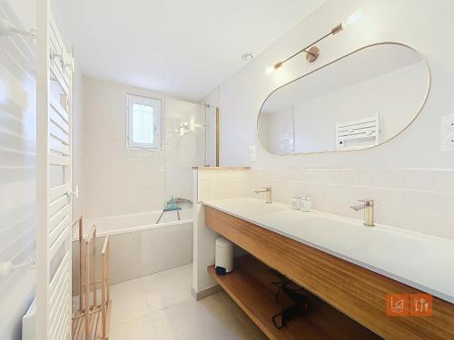 une salle de bain blanche avec un lavabo et un miroir dans l'établissement Au Ptit Bouchon Villa Golf, à Wimereux
