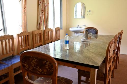 a dining room with a table and chairs and a sink at RAHUL Homestay in Sainj