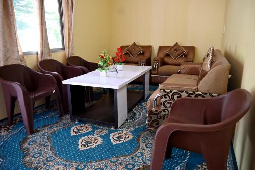 a waiting room with chairs and a table with flowers on it at RAHUL Homestay in Sainj