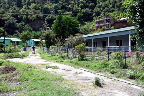 a person walking down a dirt road next to a building at RAHUL Homestay in Sainj