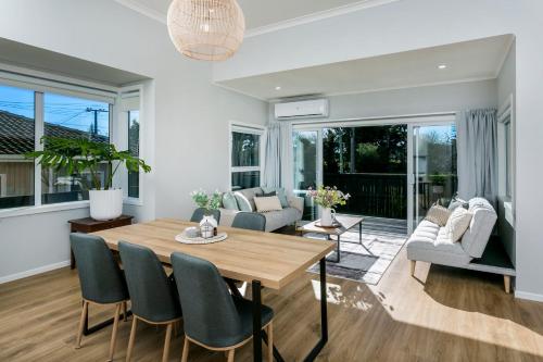 una sala da pranzo e un soggiorno con tavolo e sedie di Eden St Lukes Cozy Accommodation ad Auckland
