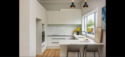 una cucina con mobili bianchi, tavolo e sedie di Eden St Lukes Cozy Accommodation ad Auckland