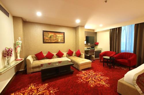 a living room with a couch and red pillows at Hotel Harmony Inn in Meerut