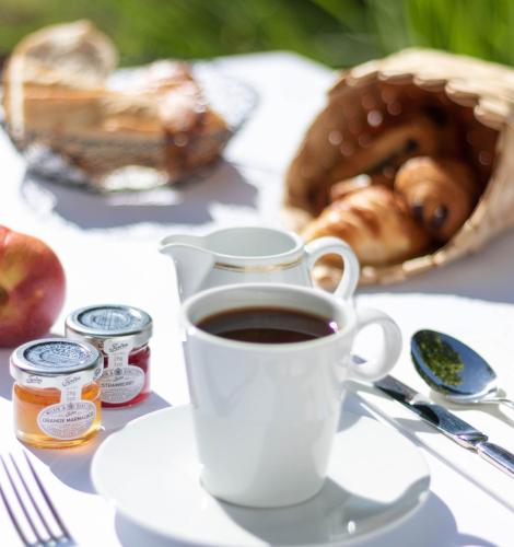 a cup of coffee on a table with a basket of bread at Le Grand Hôtel - Domaine De Divonne in Divonne-les-Bains