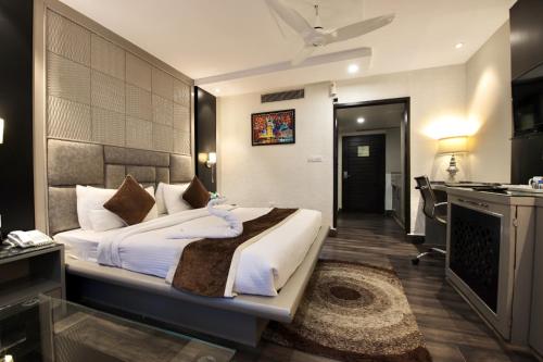 a bedroom with a bed and a desk and a kitchen at Hotel Harmony Inn in Meerut
