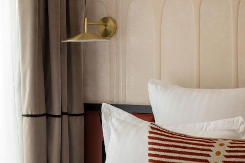 a bed with a pillow and a lamp next to a window at Hotel Grand Coeur Latin in Paris