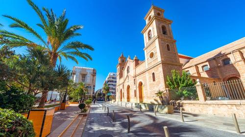 a church with a clock tower next to a street at Blue house 1ª linea playa in Torrevieja