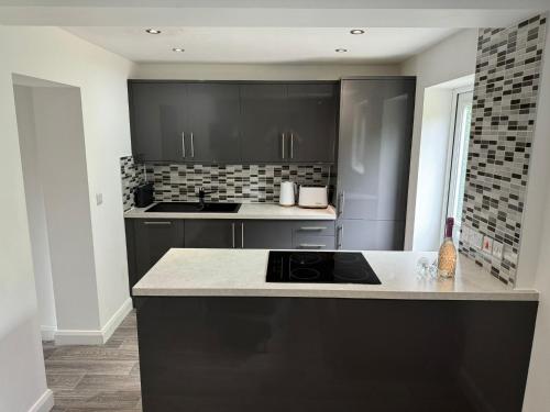 a kitchen with black cabinets and a counter top at 2 Bed Apartment Scarisbrick Street Ormskirk - Rooms by Vici in Ormskirk