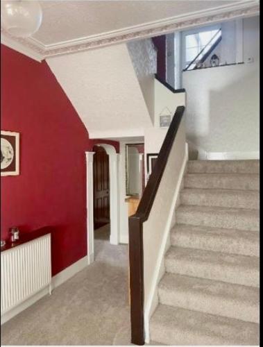 a staircase in a house with a red wall at The Old Manse B&B in Thurso
