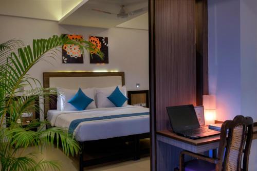a bedroom with a bed and a desk with a laptop at TreeHouse Neptune in Panaji