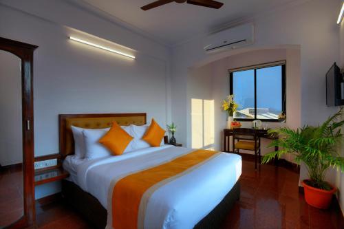 a bedroom with a large bed with orange pillows at TreeHouse Neptune Inn in Panaji