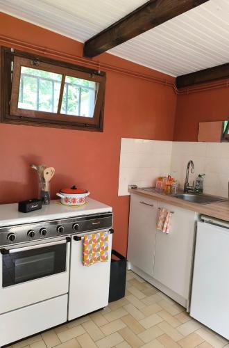 - une cuisine avec des murs rouges et une cuisinière blanche dans l'établissement Nuit étoilée en pleine Nature, à Solignac