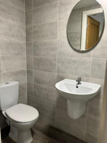 a bathroom with a toilet and a sink and a mirror at 2 Bed Apartment Scarisbrick Street Ormskirk - Rooms by Vici in Ormskirk