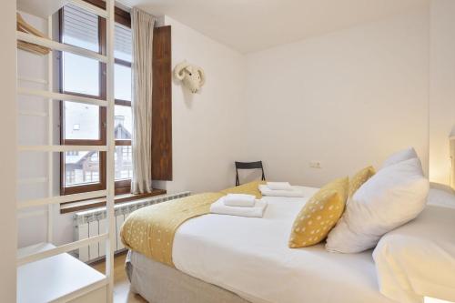una camera da letto con un letto con cuscini e una finestra di Luderna - Apartamento Aiguestortes a Vielha