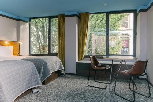 a bedroom with a bed and two chairs and a table at Bullitt Hotel in Belfast