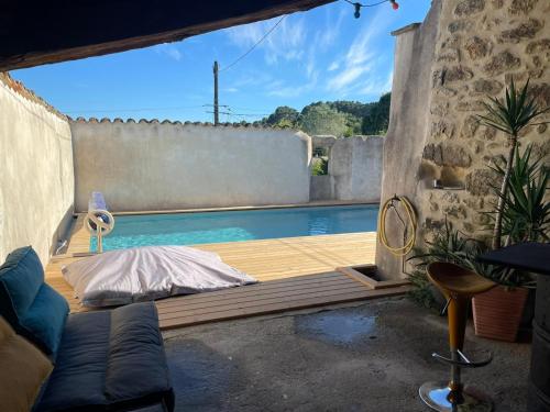 une piscine avec un lit sur une terrasse en bois dans l'établissement La Trêve - Mas 12 personnes rénové avec Piscine, à Saint-Julien-du-Serre