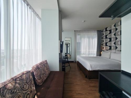 a hotel room with a bed and a couch at Luminor Hotel Jemursari By WH with The Best Breakfast in Town and Located Near Surabaya Industrial Estate Rungkut SIER in Surabaya