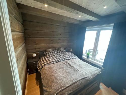 a bedroom with a bed with a wooden wall at Cabin with Porsche to rent in Sogndal
