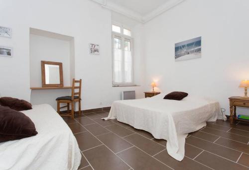 Cette chambre blanche comprend 2 lits et un miroir. dans l'établissement A 5' de la plage, à Cannes