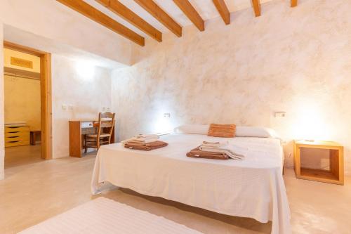 a bedroom with a white bed and a table at Can Jeroni Carrio in Cala Bona