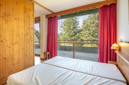 une chambre avec un lit et une grande fenêtre dans l'établissement Le Chamroussien - Appt 6p, au pied des pistes, à Chamrousse