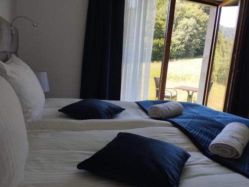 two beds with blue pillows and a window in a room at ELFF -Apartamenty i pokoje gościnne in Cisna