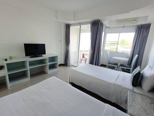 a hotel room with two beds and a television at KP Seaview Jomtien in Na Jomtien