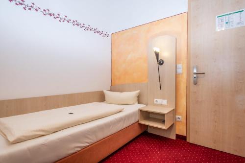 a small room with a bed and a door at Hotel Alte Post in Siegsdorf