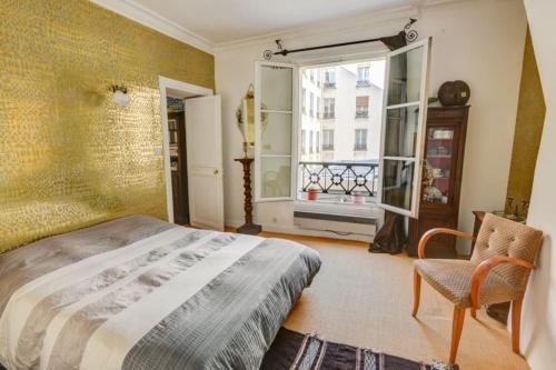 une chambre avec un lit, une fenêtre et une chaise dans l'établissement Coeur Paris authentique, à Paris