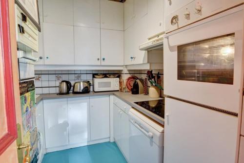 une cuisine avec des armoires blanches et un micro-ondes dans l'établissement Coeur Paris authentique, à Paris