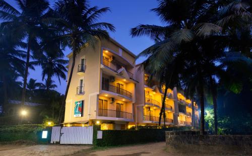 un gran edificio blanco con palmeras por la noche en TreeHouse Blue Hotel & Serviced Apartments, en Majorda