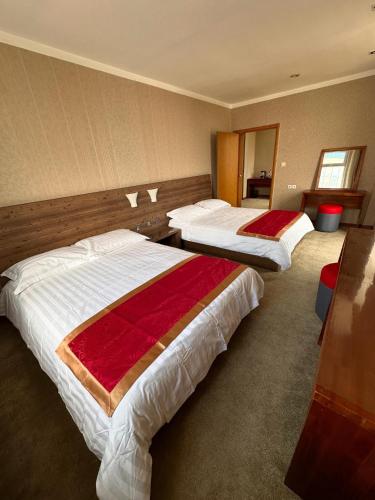 a hotel room with two beds with red and white sheets at Zuut hotel in Ulaanbaatar