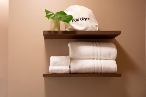 une étagère avec des serviettes et une plante sur elle dans l'établissement Cà Bèla - Susa, à Milan